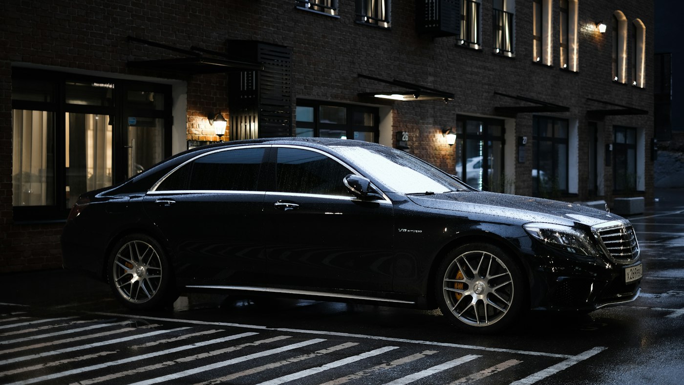 Berline Mercedes-Benz noire garée en ville le soir